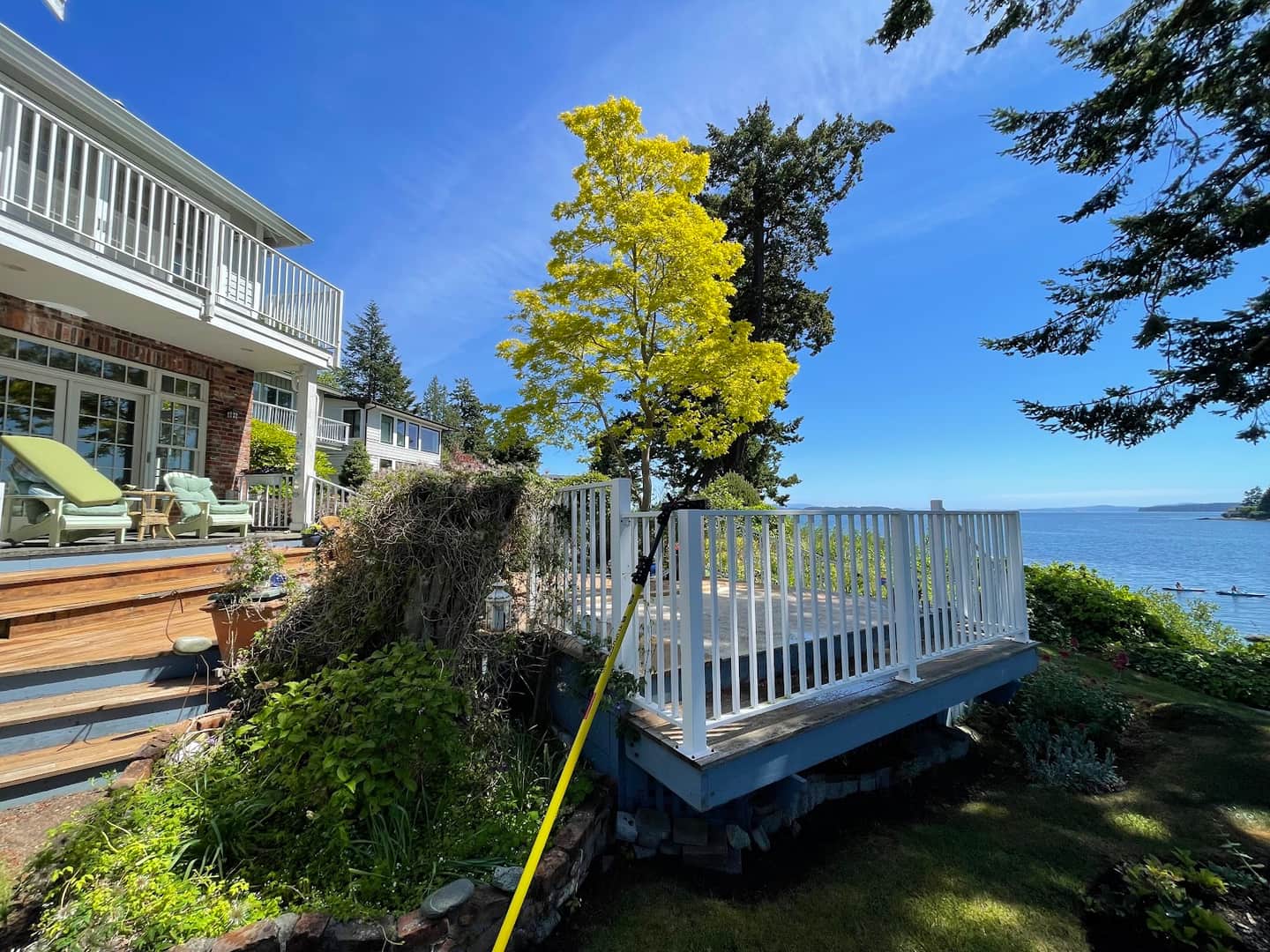 Island Shine cleaning windows with a water-fed pole at an oceanfront home on Vancouver Island